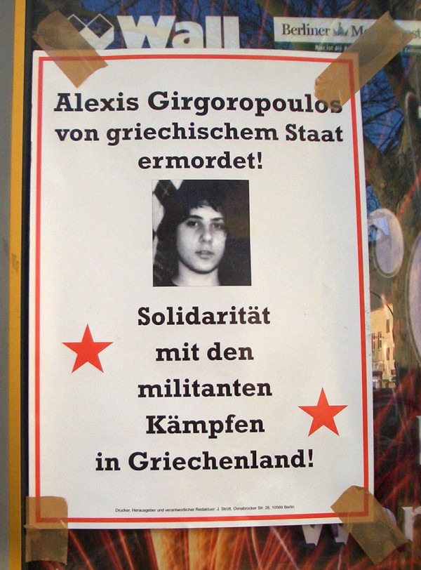 Ein Plakat mit einem Schwarz-Weiß-Foto eines jungen Menschen. Der Text lautet: "Alexis Grigoropoulos von griechischem Staat ermordet! Solidarität mit den militanten Kämpfen in Griechenland!" Rote Sterne flankieren den Text.
