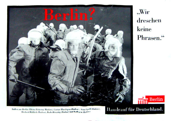 Ein schwarz-weißes Plakat zeigt eine Gruppe von Bereitschaftspolizisten mit Helmen und Schlagstöcken. Oben steht in roter Schrift: "Berlin?". Auf der rechten Seite: "Wir dreschen keine Phrasen". Unten: "Haudrauf für Deutschland" mit einem roten Berlin-Logo.
