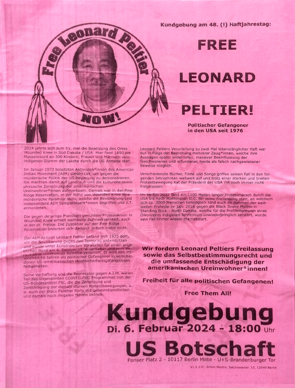 Das Poster ist rosa mit einem schwarz-weißen Bild von Leonard Peltier in einem Kreis, umrahmt von den Worten "Free Leonard Peltier Now!" Federn hängen an den Seiten des Kreises. Rechts steht in großen schwarzen Buchstaben: "Free Leonard Peltier! Politischer Gefangener in den USA seit 1976." Darunter sind weitere Informationen über seine Verurteilung und die Forderung nach seiner Freilassung. Unten steht: "Kundgebung Di. 6. Februar 2024 - 18:00 Uhr US Botschaft." Der Text ist in schwarzer Schrift.