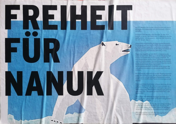 Ein Plakat mit einem weißen Eisbären auf blauem Hintergrund. Der fette schwarze Text lautet "FREIHEIT FÜR NANUK". Ein kleinerer Text in deutscher Sprache befindet sich auf der rechten Seite. Das Design ist einfach und auffällig.