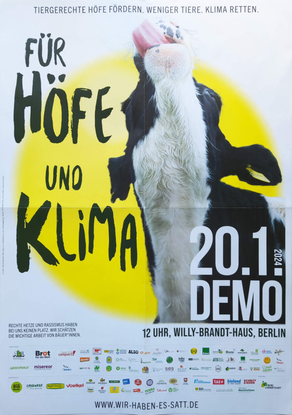 Ein Plakat mit einem schwarz-weißen Kuhkopf, der die Zunge herausstreckt. Der Hintergrund ist gelb. Oben steht: "Tiergerechte Höfe fördern. Weniger Tiere. Klima retten." In großen, schwarzen Buchstaben: "Für Höfe und Klima". Rechts in weißer Schrift: "20.1.2024 Demo". Weitere Infos: "12 Uhr, Willy-Brandt-Haus, Berlin". Unten ein Satz gegen Rassismus und Logos verschiedener Organisationen. Webseite: www.wir-haben-es-satt.de.
