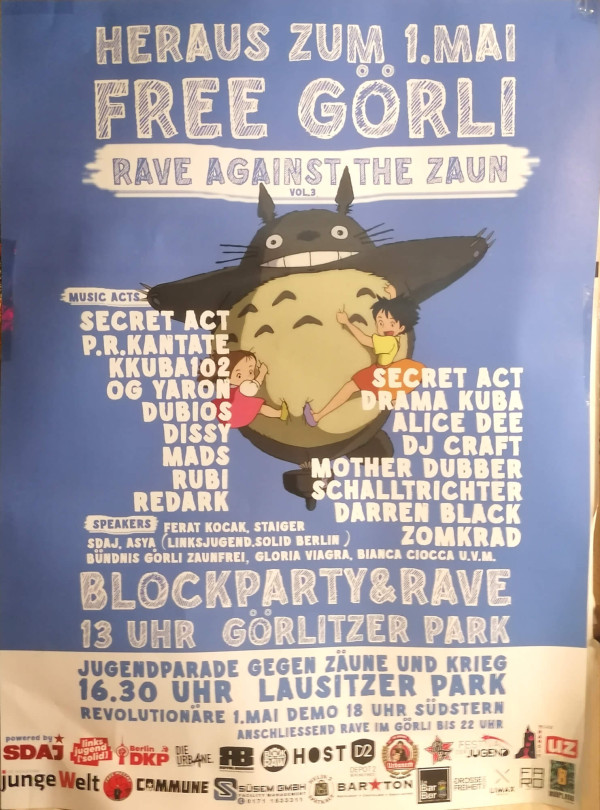 Ein blaues Poster mit der Überschrift "Heraus zum 1. Mai Free Görli Rave Against The Zaun Vol.3". Ein großes, graues, katzenähnliches Wesen steht in der Mitte, umgeben von zwei Kindern. Musik-Acts wie Secret Act, P.R.Kantate und andere sind aufgelistet. Sprecher sind Ferat Kocak und andere. Unten steht "Blockparty & Rave 13 Uhr Görlitzer Park". Ein weißer Abschnitt enthält Details zur Jugendparade um 16:30 Uhr im Lausitzer Park. Verschiedene Logos sind am unteren Rand.