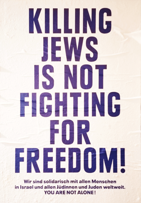Weißes Plakat mit fettgedrucktem, violettem Text: "Juden zu töten ist kein Kampf für die Freiheit!" Darunter, in kleinerer Schrift, steht: "Wir sind solidarisch mit allen Menschen in Israel und allen Jüdinnen und Juden weltweit. Ihr seid nicht allein!"