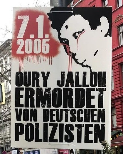 Ein Plakat mit einer schwarz-weißen Illustration eines Gesichts mit roten Streifen. Der Text lautet: "7.1.2005 Oury Jalloh ermordet von deutschen Polizisten", auf weißem Hintergrund.