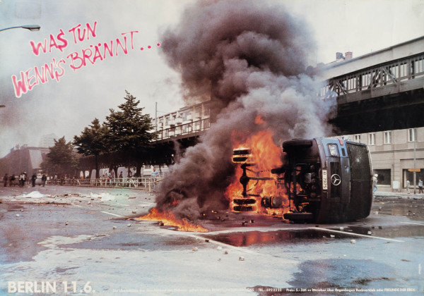 Ein Plakat zeigt ein umgestürztes, brennendes Fahrzeug mit dichtem Rauch vor einer Stadtkulisse. Der Text lautet: "Was tun wenn's brennt... Berlin 11.6." Das Design ist kühn mit feurigen Farben.